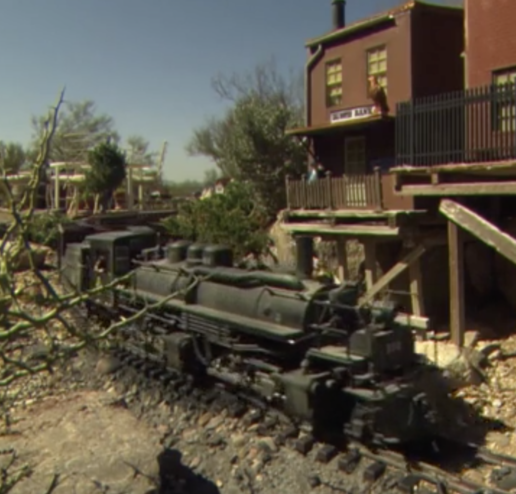 Garden scale steam locomotive moving through a Western US themed outdoor layout.