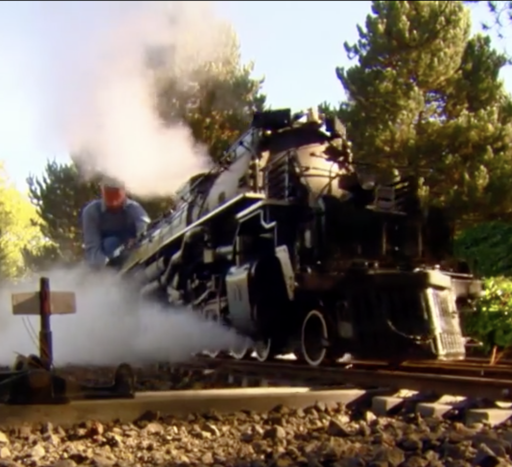 Man riding atop a scale 4-8-8-4 live steam locomotive.