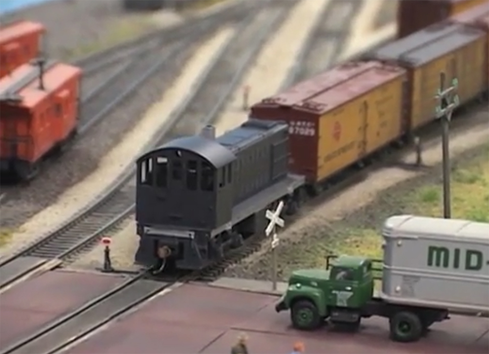 Model locomotive approaches a crossing