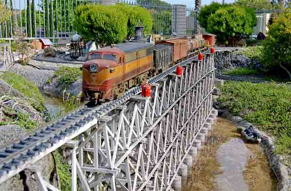 A model train running on a bridge in a garden railroad