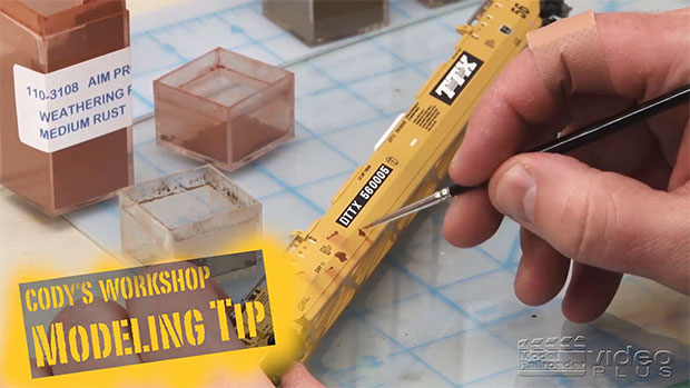 cody weathering the side of a yellow flatcar