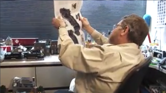 Bob Keller looking at fold-out poster of a locomotive