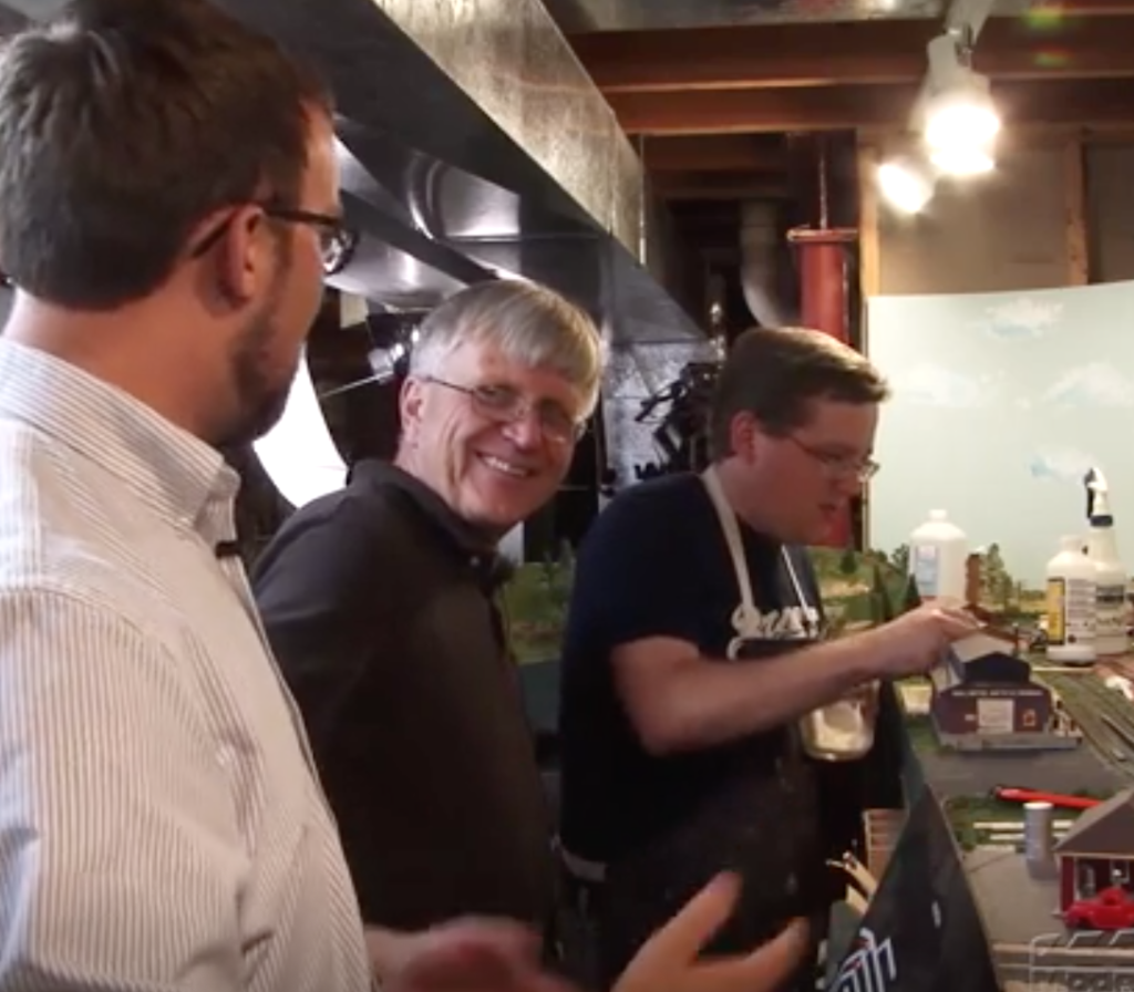 Three men working on a model railroad layout.