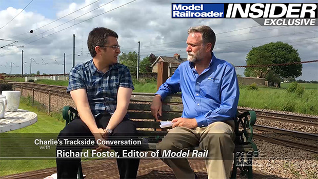 Charlie Conway and Richard Foster sitting on a bench outside next to railroad tracks