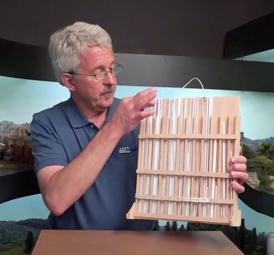 Glasses wearing man holding a tray of scale of organized scale lumber pieces.