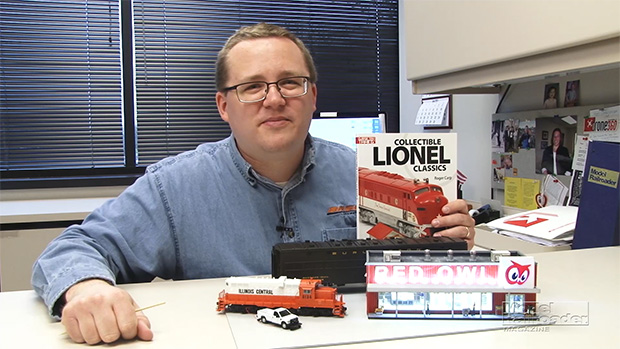 Cody sitting at his desk, smiling, while holding the collectible lionel classics book