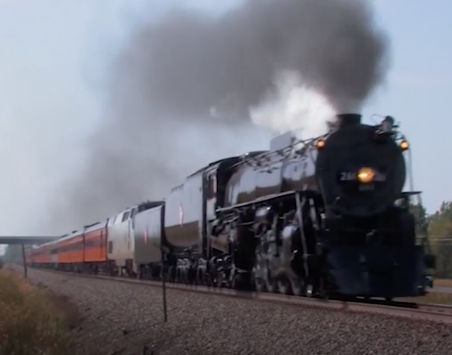 Large black steam locomotive hauling passenger train.