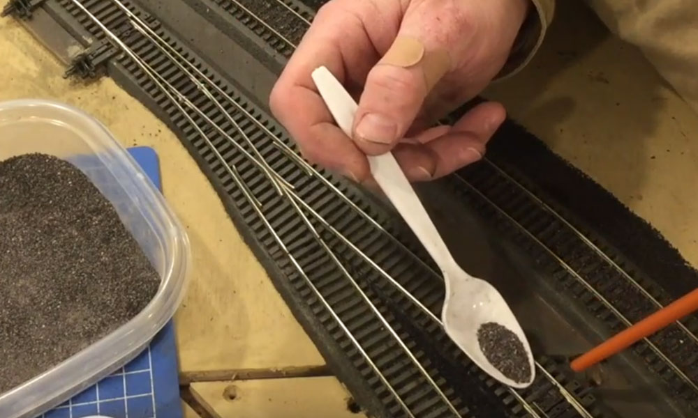 Hand adding ballast to model track