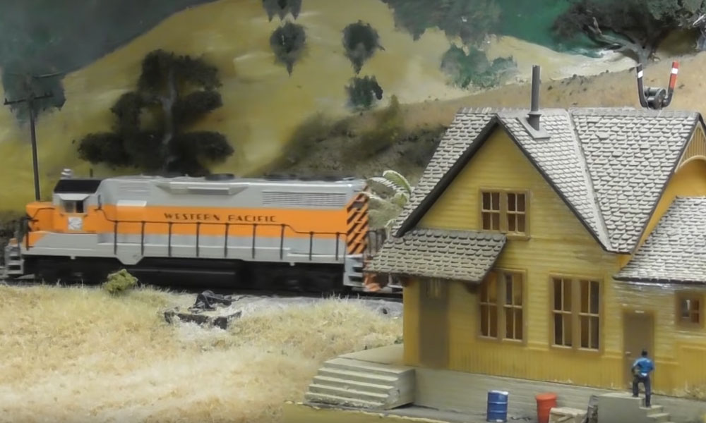 Model locomotive passing a house