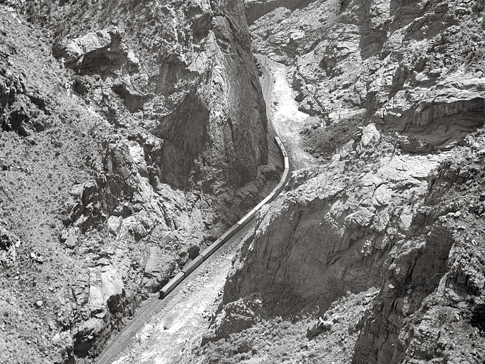 A black and white photo of a train deep in a ravine