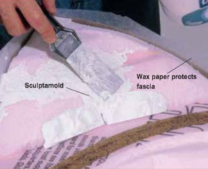 Hand filling gaps in plaster with putty knife