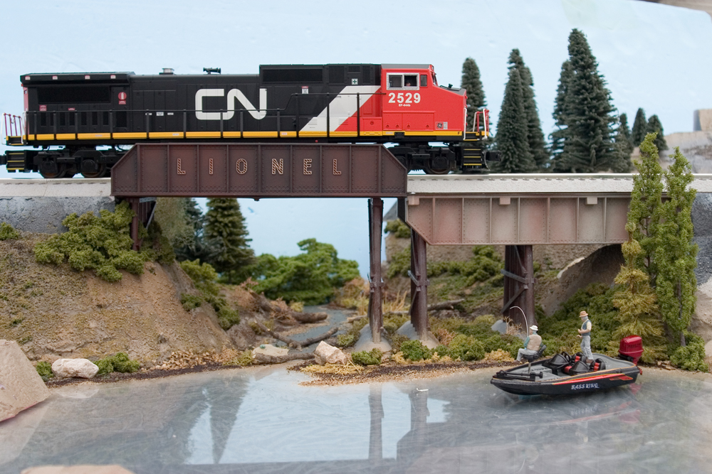 A CN diesel toy train going over a bridge with a river underneath