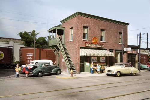 A model scene showing a brick building grocery and vintage cars