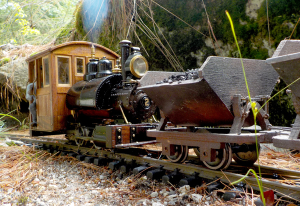 A small engine pushing a small coal cart on a garden layout