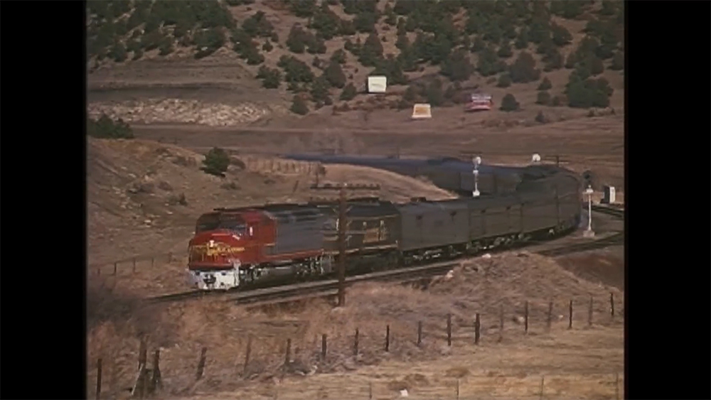 A screen shot of an old video showing a red bnsf diesel locomotive