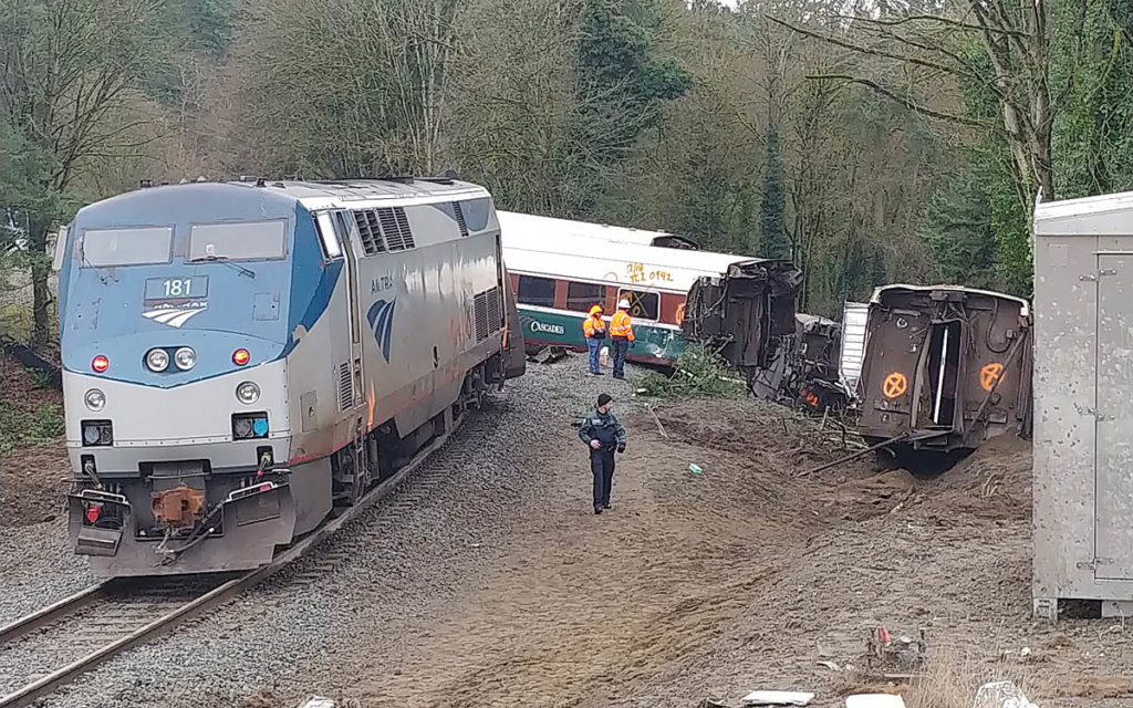 Locomotive stopped on tracks with derailed cars in background