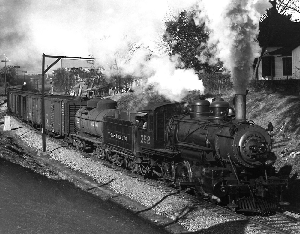 A black and white photo of ten-Wheeler 352 locomotive on the track with steam coming out of its chimney