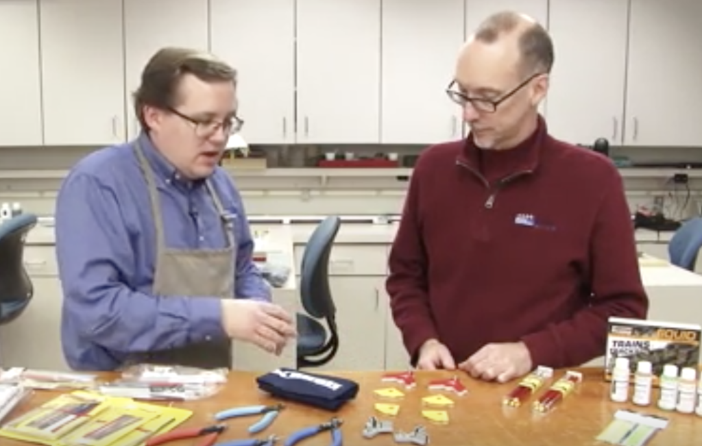 Two men with model products at a table.