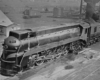 a streamlined steam engine in a rail yard