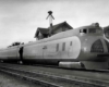 Three-unit streamlined passenger train poses in front of station