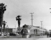 Passengers watch early streamlined passenger train by palm trees