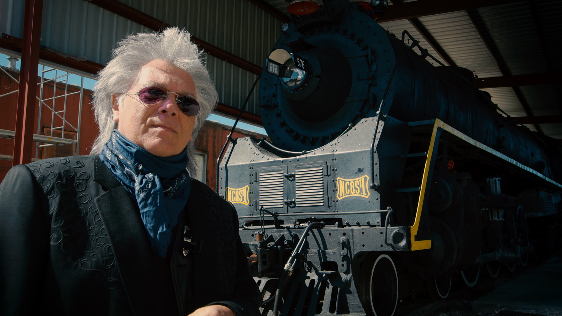 Musician Marty Stuart standing in front of locomotive