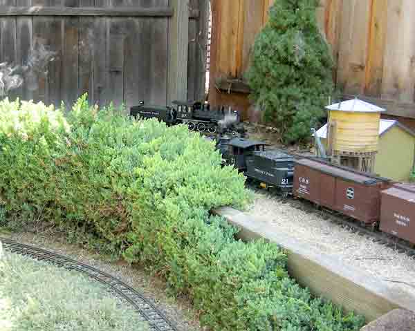 section of garden railroad with fence in the background
