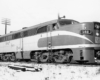 A black and white close up photo of Nickel Plate’s 11 Alco with the conductor inside the train