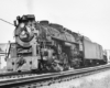 A close up black and white photo of a 2-8-4 fast freight steam locomotive moving on the tracks