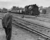A man standing, looking at a train