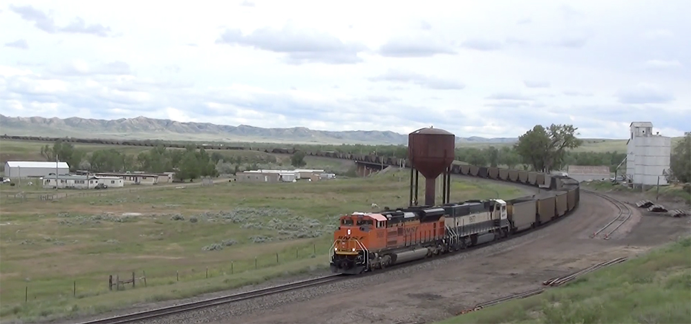 Freight train winds through wide open prairie.