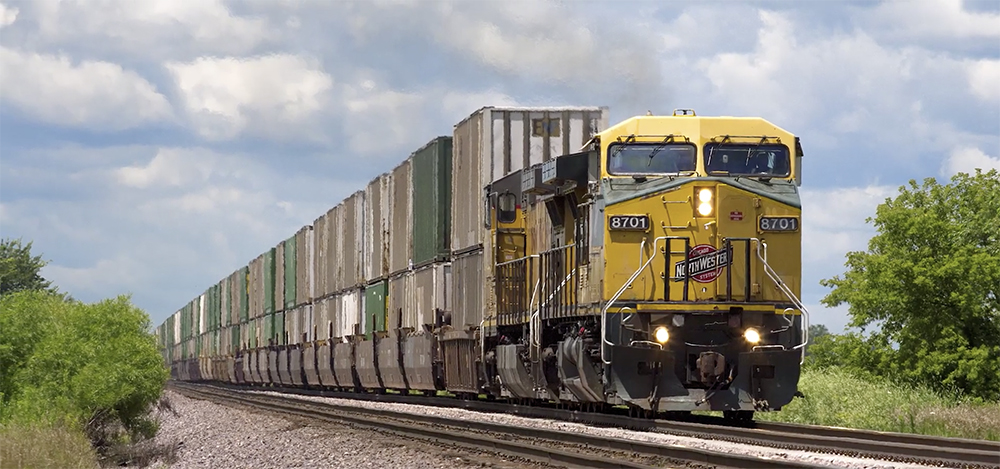 A yellow-painted locomotive hauls a freight train .