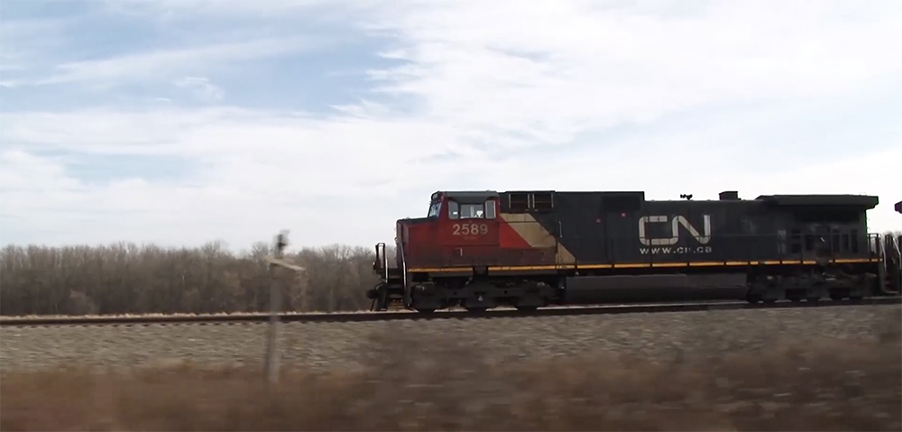 A black-and-red Canadian National locomotive parses dry grasslands of Wisconsin.