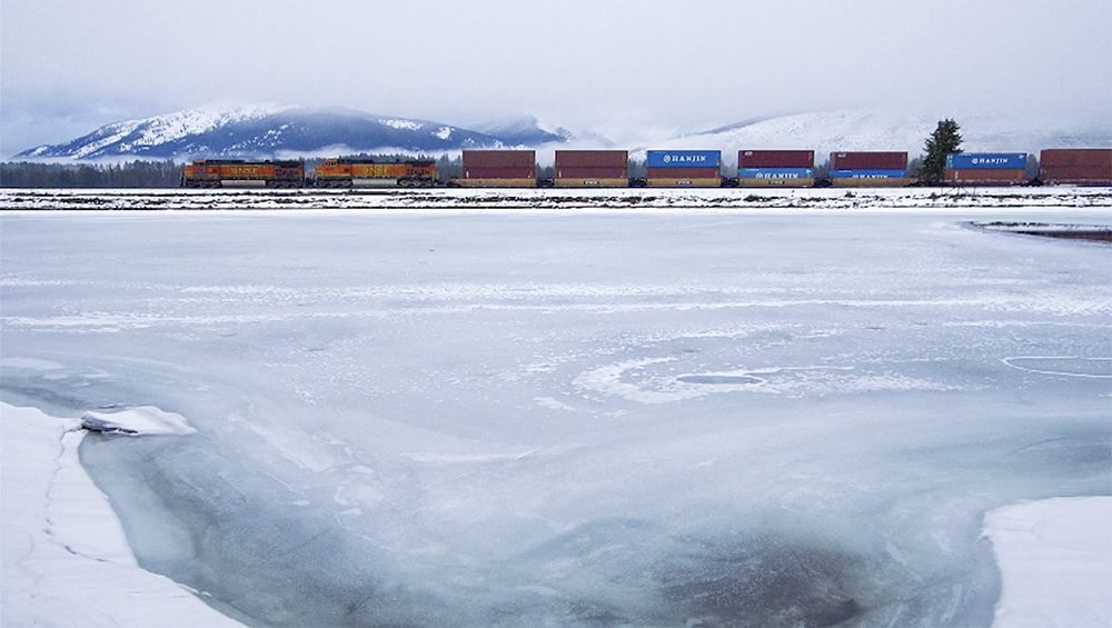 A freight train crosses a snowy landscape.