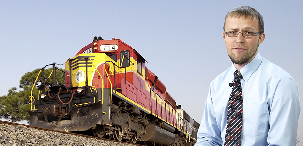 Drew Halverson poses with a vividly painted red-and-yellow Florida East Coast locomotive.