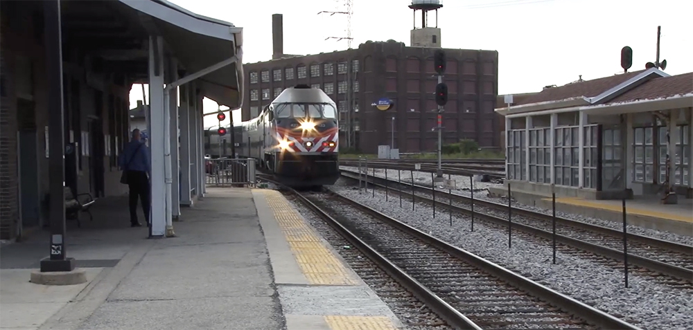 A round-nosed diesel passenger locomotive rounds a corner in a busy freight yard.