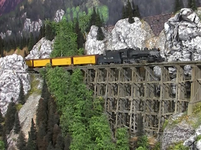 a steam engine pulling freight cars over a bridge