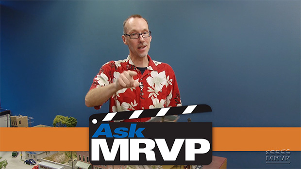 David Popp wearing a Hawaiian shirt and standing next to a model railroad.