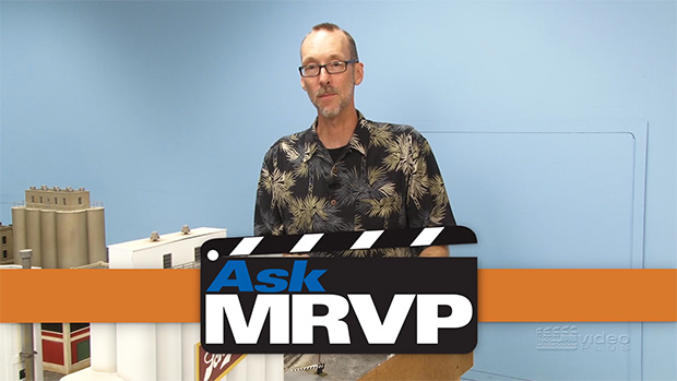David Popp wearing a Hawaiian shirt standing next to an O gauge layout.