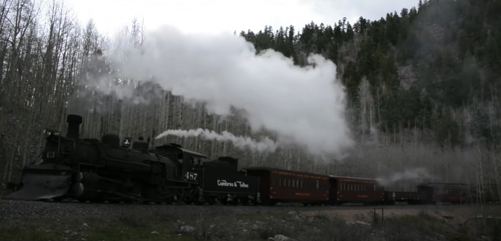 Cumbres & Toltec No. 487 steam locomotive traveling through a heavily forested landscape