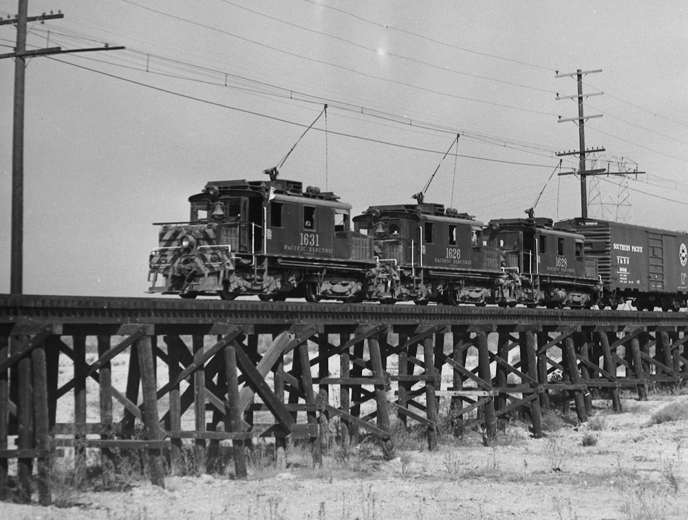 Three freight motors haul a freight train over a trestle.