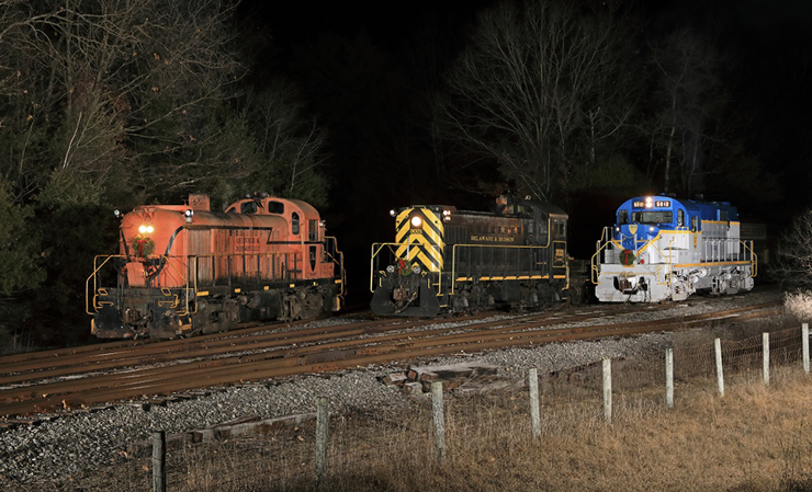 Three older diesel locomotives aligned on yard tracks for a night time photo session.