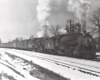 Two steam locomotives lead a freight train in a snowy scene.