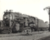 A large 2-10-2 steam locomotive hauling tank cars.