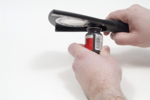 One hand grips a black-colored Oxo jar opener while another hand holds a paint jar.