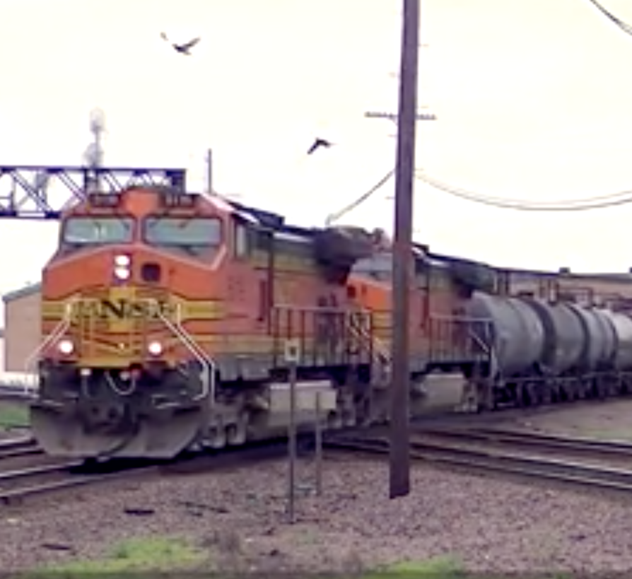 An orange painted diesel locomotive leads a train over a double-diamond.