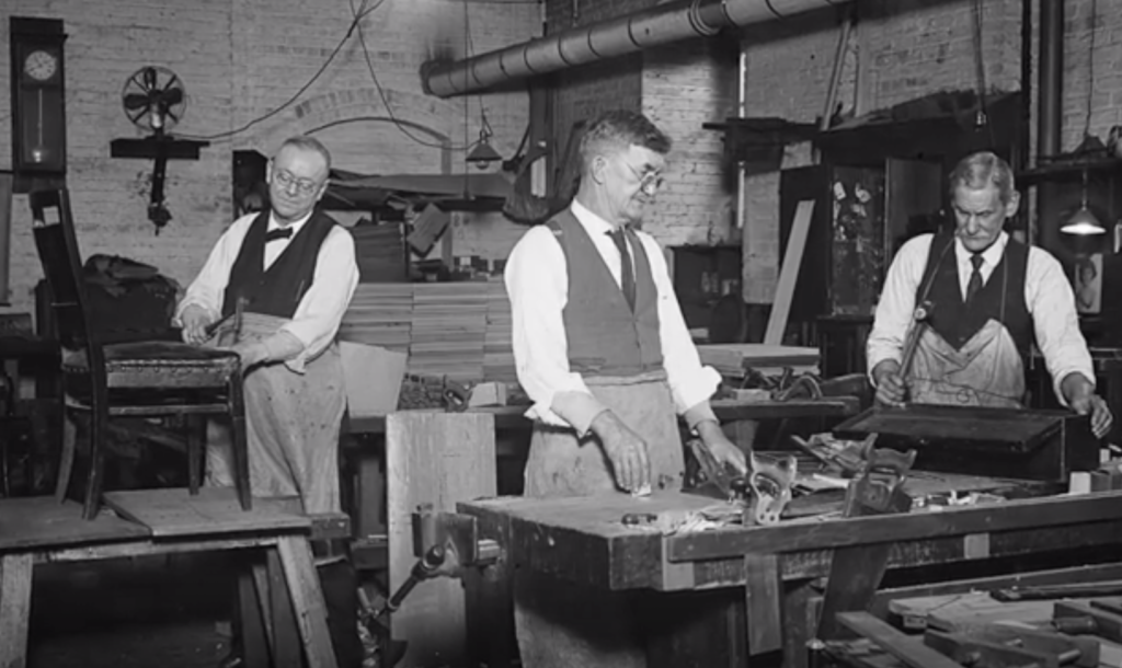 Black and white image of craftsmen wearing ties and in a woodshop.