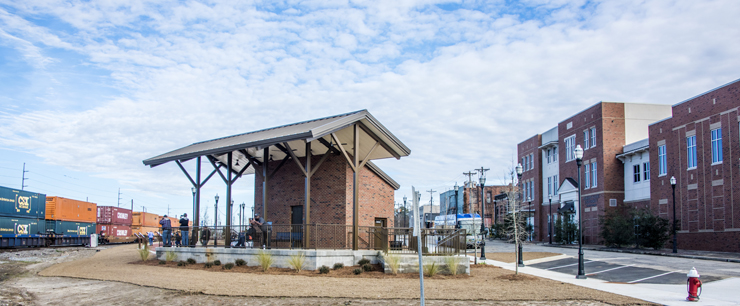 Brick pavilion between train tracks and downtown buildings