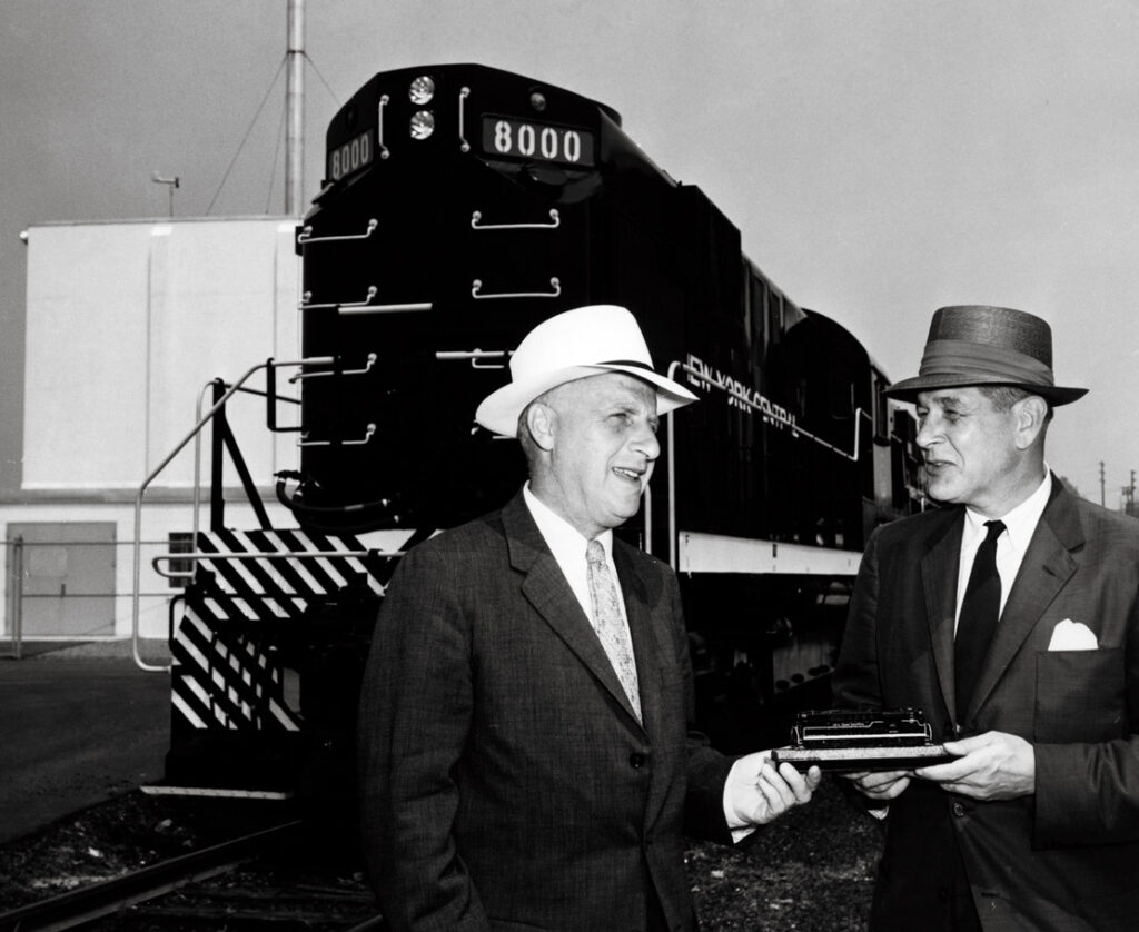Two men in front of road-switcher diesel locomotive