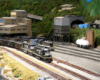 A pair of black diesels lead a loaded coal train while a diesel switcher works a mine in the background
